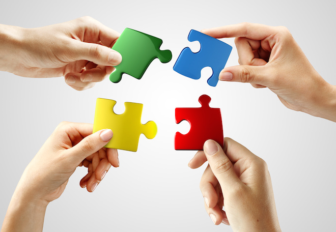 Hands and puzzle on gray background. Teamwork solving a puzzle